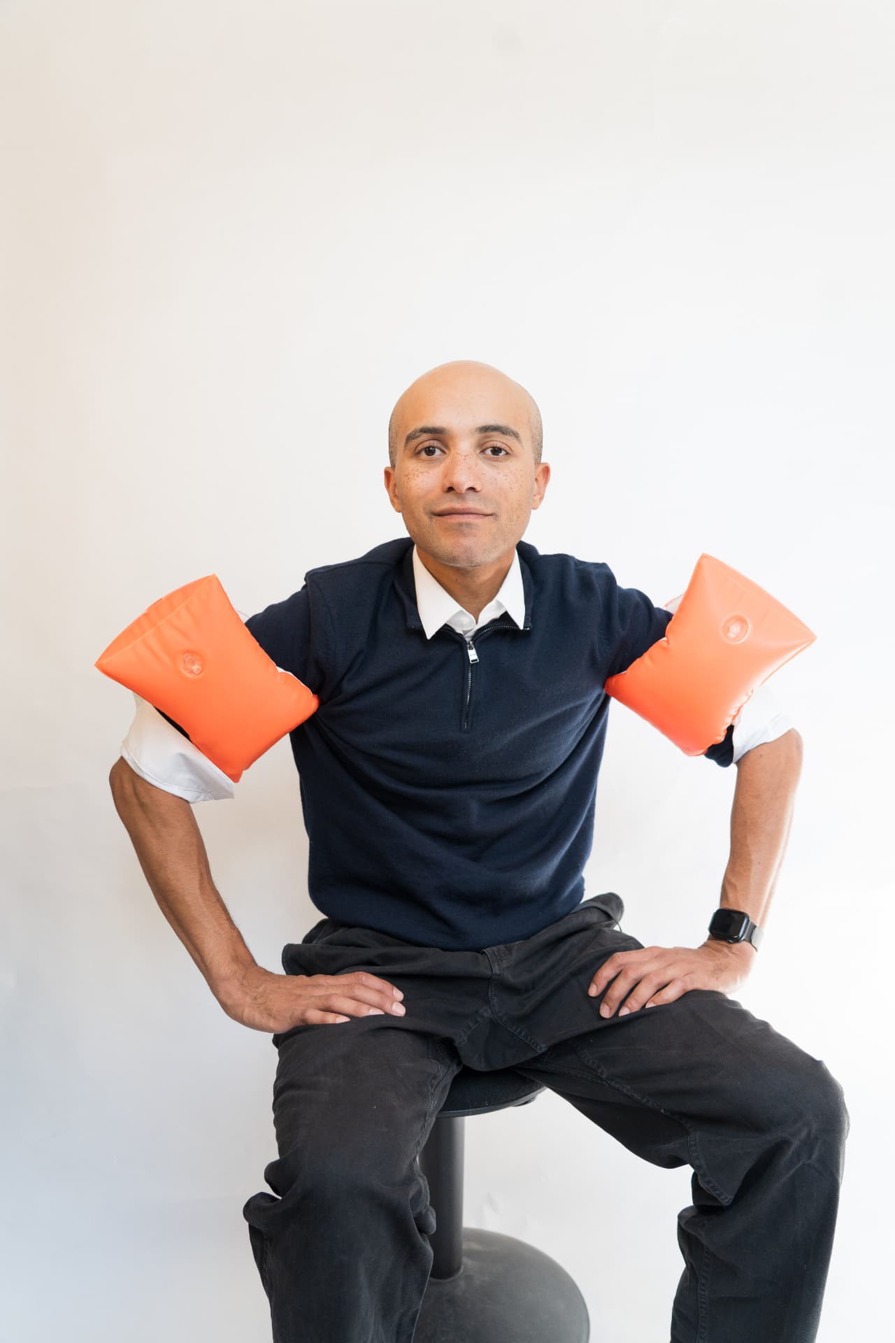 Yves sitzt mit orangen Schwimmflügeln auf einem Hocker